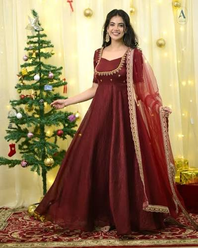 Floor-length wine anarkali gown with a full flare and sweetheart neckline, worn with a matching net dupatta edged in gold lace.