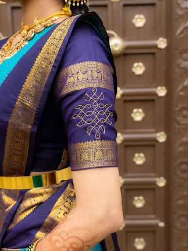 Close-up of a deep purple Kanjeevaram blouse sleeve cut from the saree's own gold zari border, with a white kolam motif embroidered at the centre.