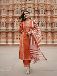 Rust orange kurta with woven cream motifs, matching straight pants and a striped tasselled dupatta.